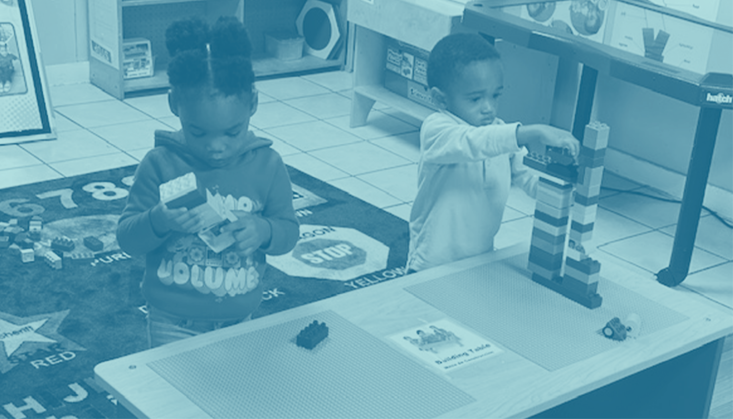 Two children playing with blocks at a table